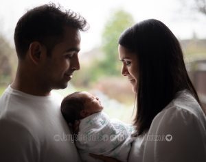 Parents and newborn silhouette against window at home