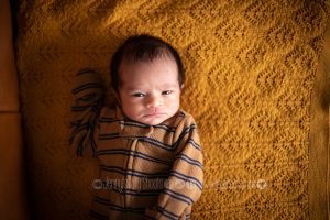 Baby newborn boy at home on mustard blanket