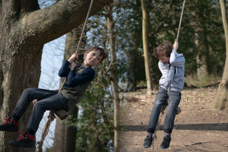 portrait of boys swinging on rope swings