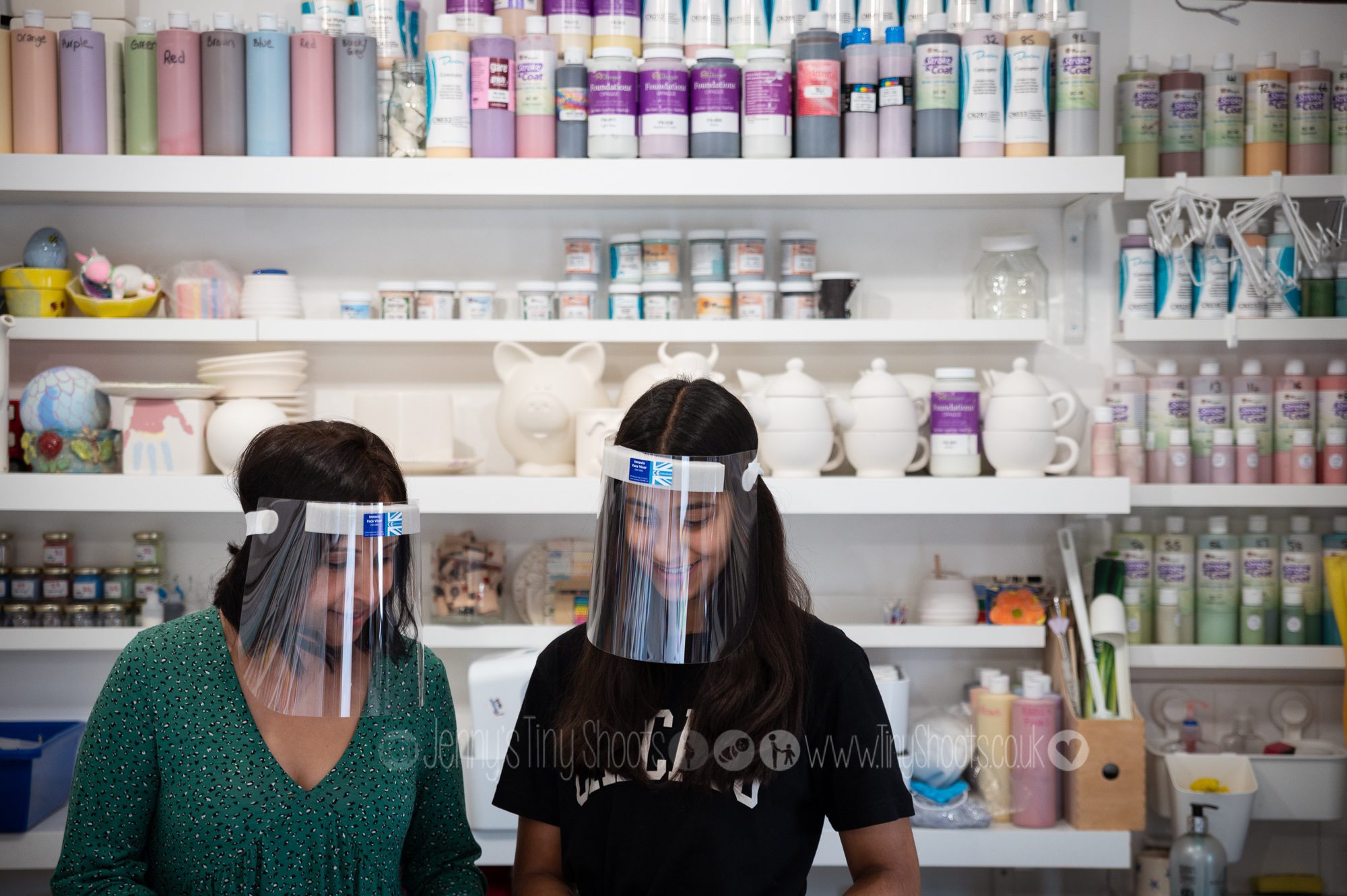 Two women with facemasks working in a pottery studio