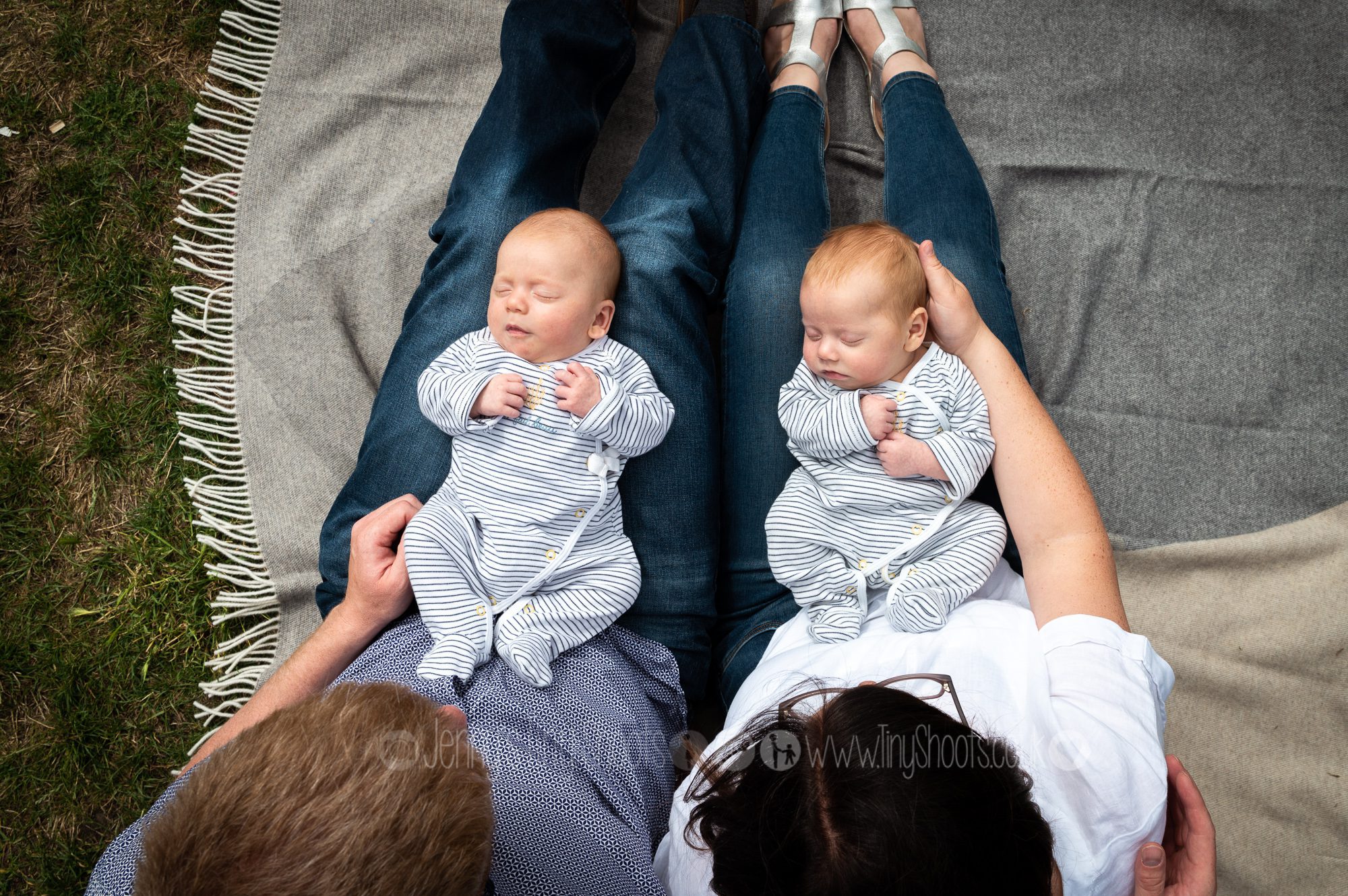 Baby twins on parents knee