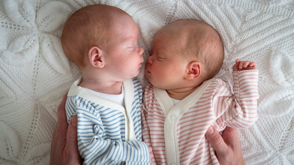 Newborn photos of twins wearing babygrows