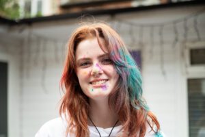 Headshot portrait of woman covered in holi paint