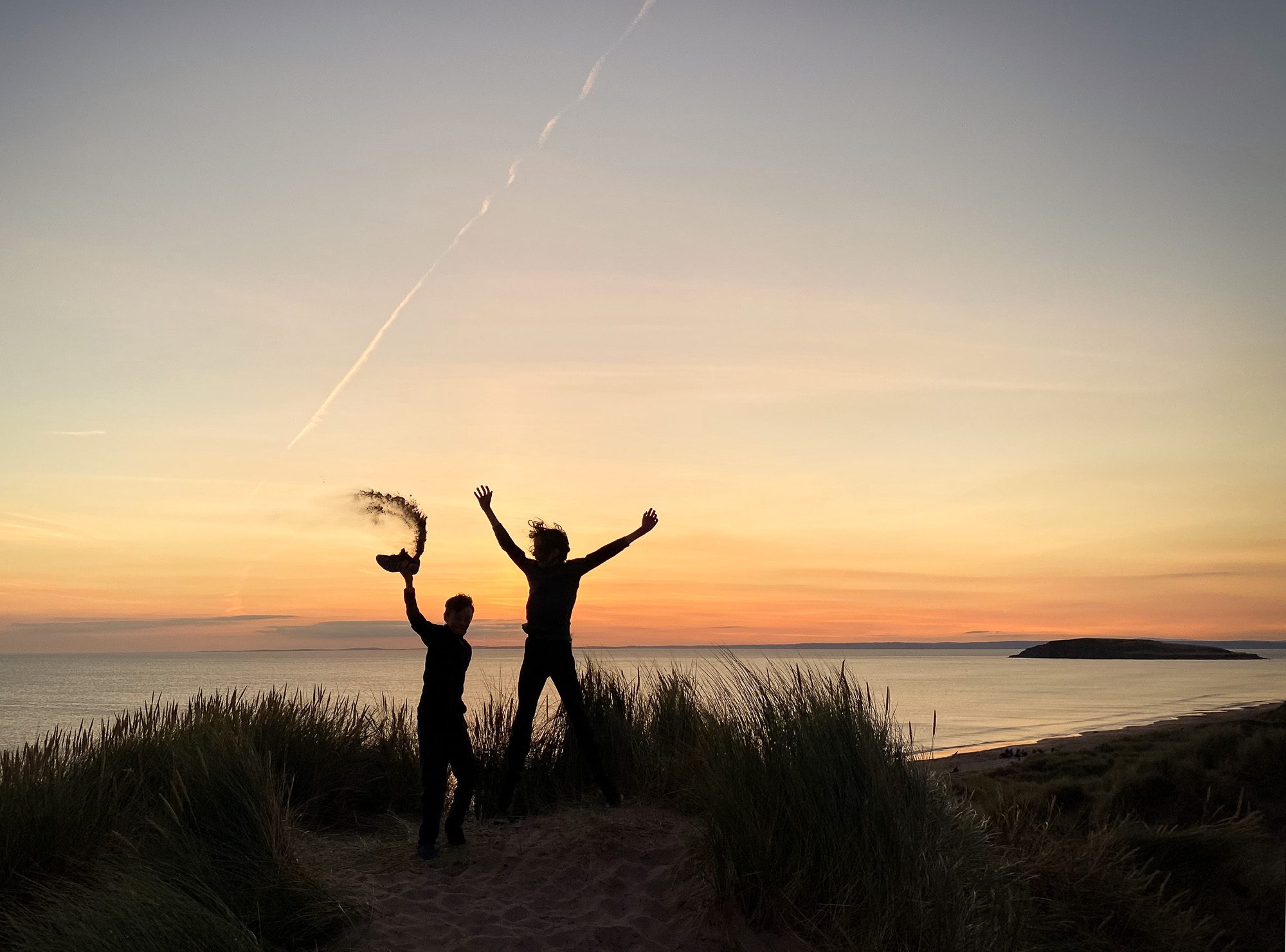 Family photo session of children jumping against sunset