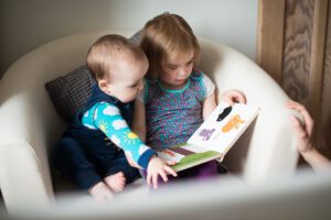 baby reading with sister