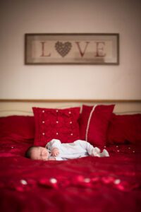 baby photographed on bed in red