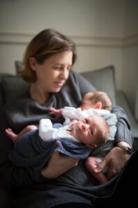 Mum holding twin newborns at home