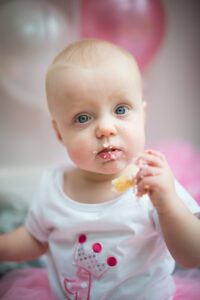 baby photography at home, baby girl with birthday cake in a family photo session