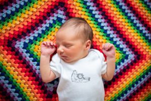 Newborn baby on rainbow blanket at home