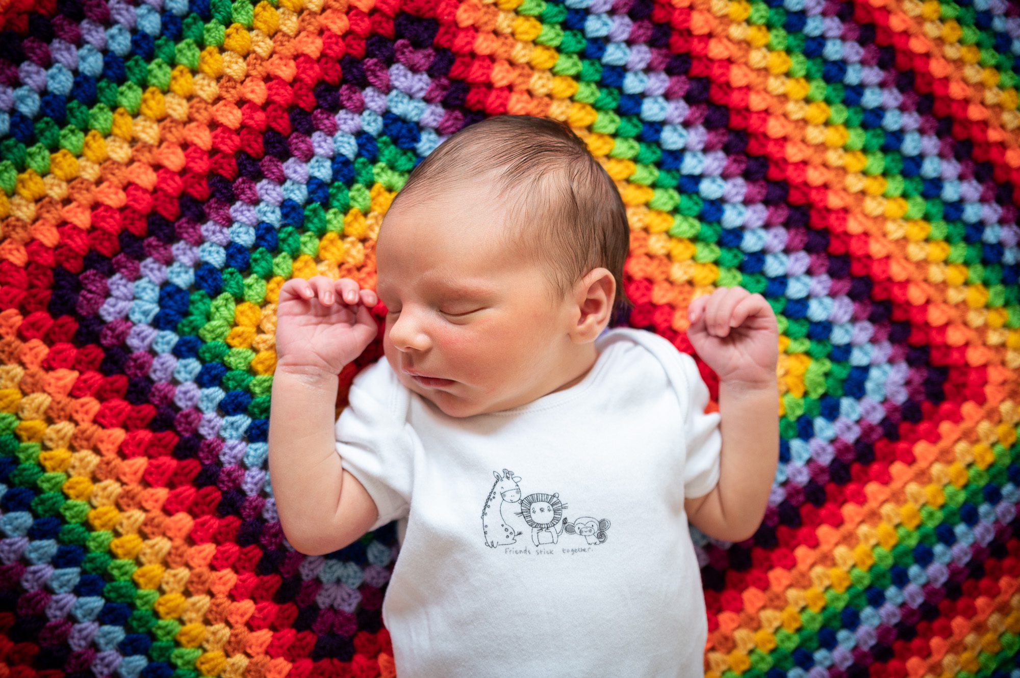 Newborn baby on rainbow blanket at home