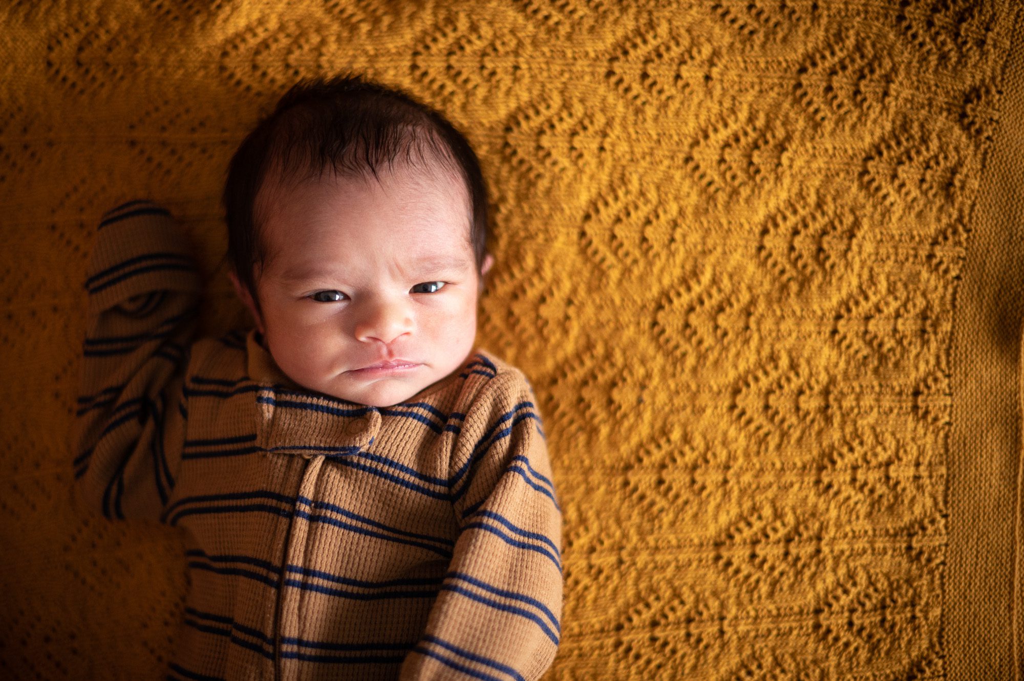 Newborn baby at home on yellow mustard blanket