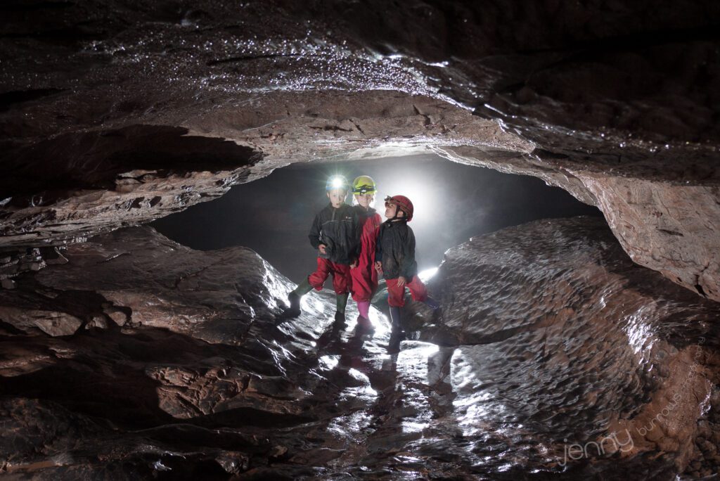 3 children standing in a cave with shadows behind