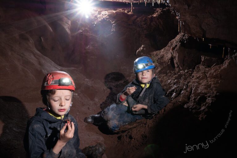 Two boys eating a snack in a cave