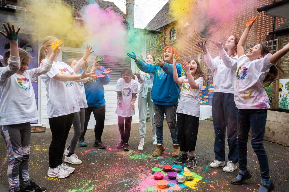 Group of children throwing coloured powder in the air