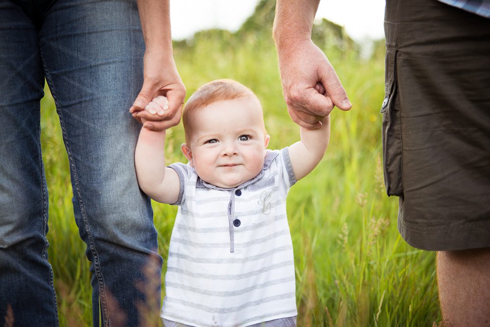 baby portrait holding hands with parents