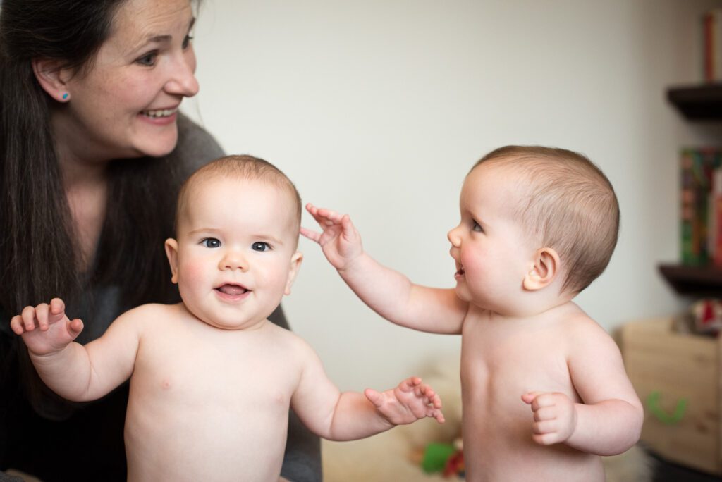 Twin babies at home learning to stand up
