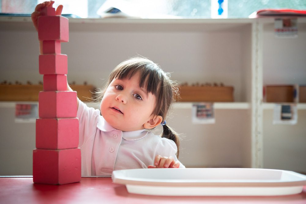 Girl portrait at montessori nursery using blocks