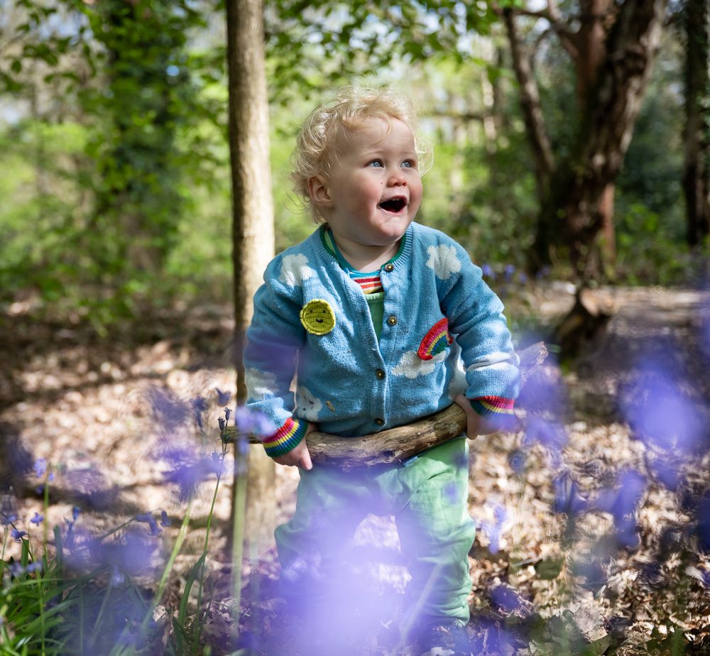 Toddler boy playing and laughing in bluebell woods