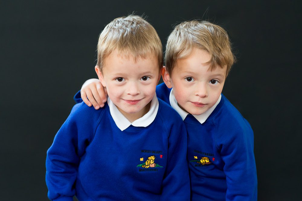 Twins siblings in nursery school photo in blue uniform jumpers