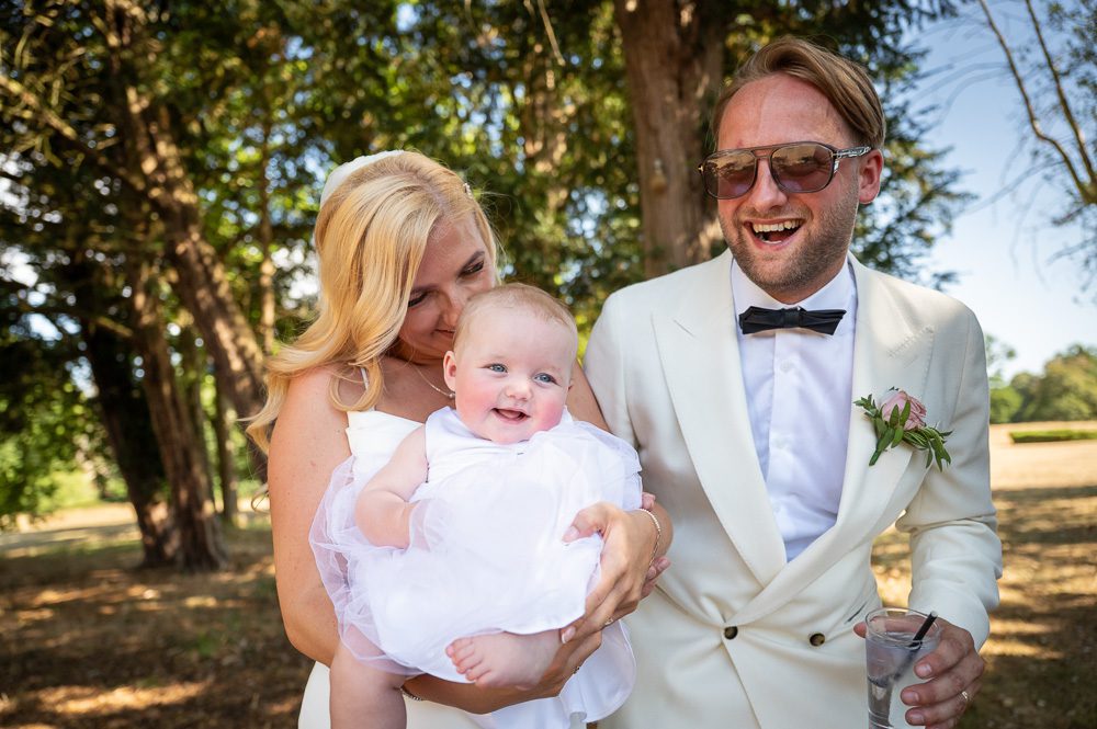 Bride and groom and baby at a summer wedding