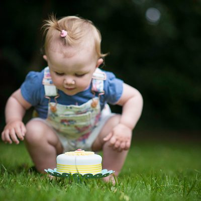 1 year old baby outdoor portrait with cake smash